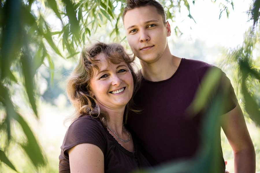 Heartwarming family portrait in a garden, depicting a mother and her transgender son, radiating joy and celebrating their shared journey.